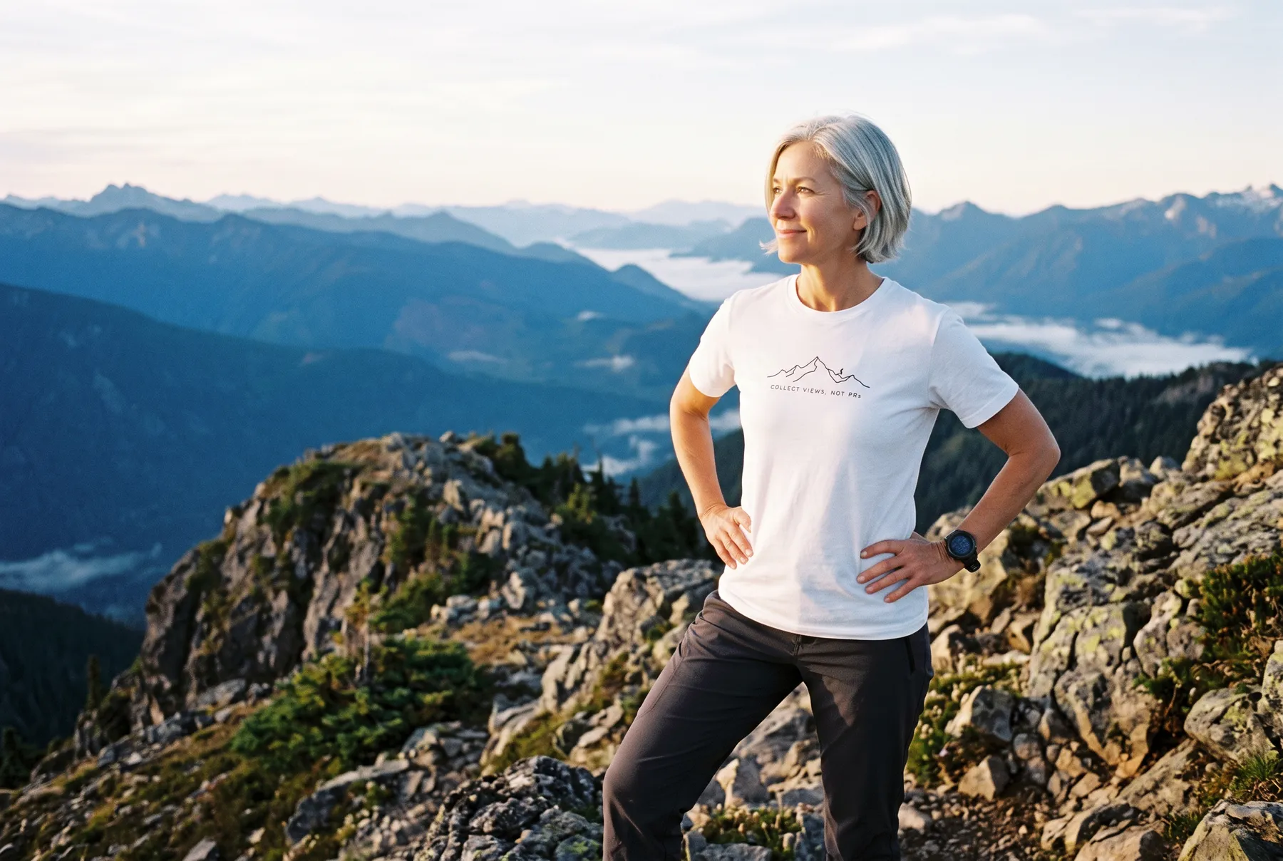 Runner on a summit at sunrise wearing the Collect Views Not PRs tee